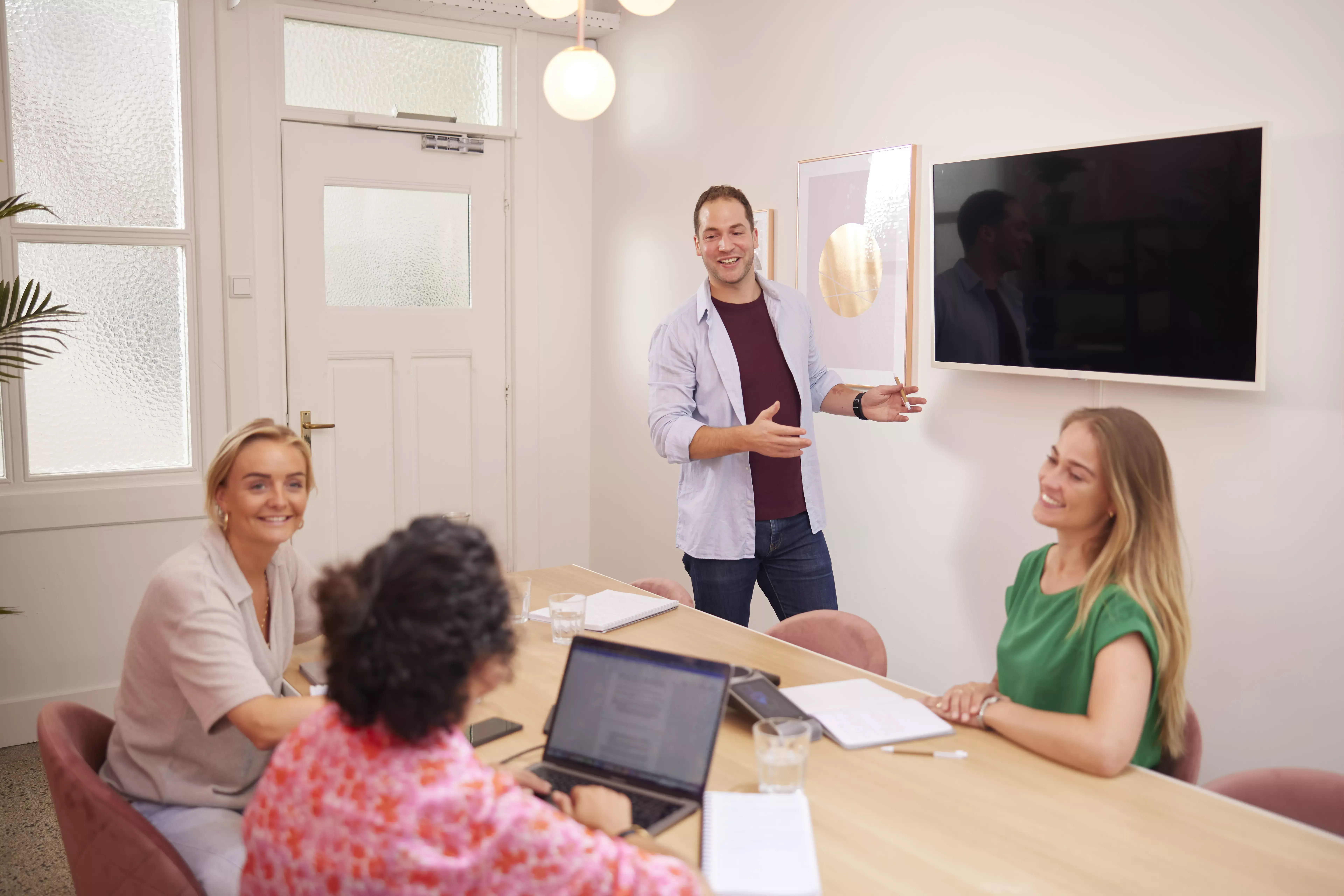 Vier mensen zijn aan het videobellen via laptop met groot scherm aan 