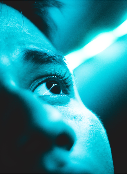 An individual looks into the distance as a blue light shines down on them