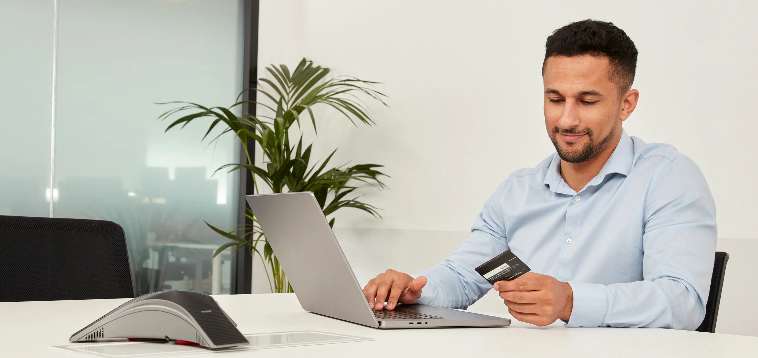 Een man in een blauw overhemd bekijkt een tankkaart terwijl hij voor zijn laptop zit.