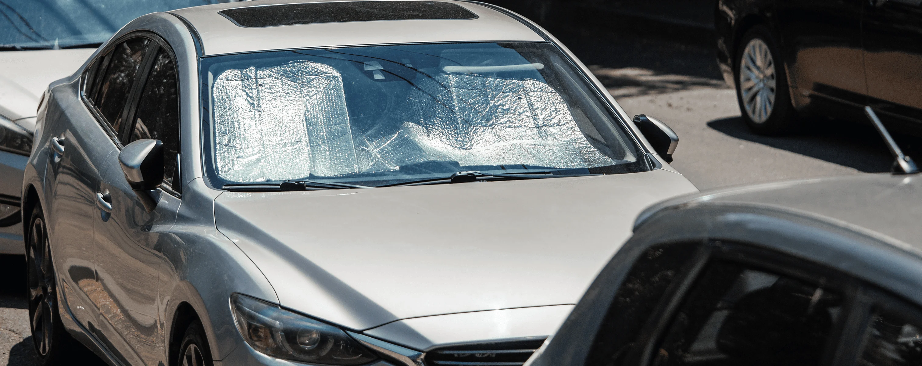 Firmenfahrzeug mit Sonnenblende zum Schutz vor Hitze auf einem Parkplatz.