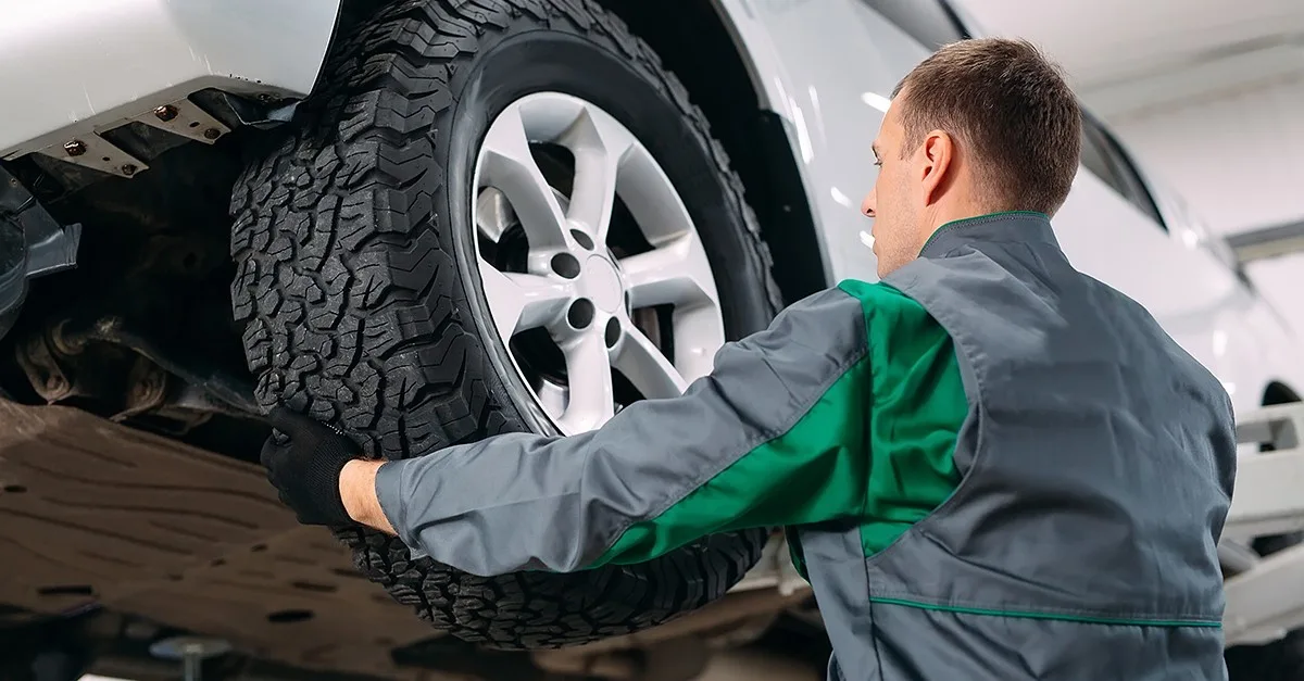 Ein Mann in der Autowerkstatt wechselt einen Reifen.