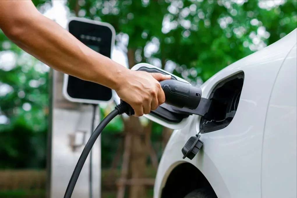 Een elektrische auto wordt opgeladen bij een laadstation.