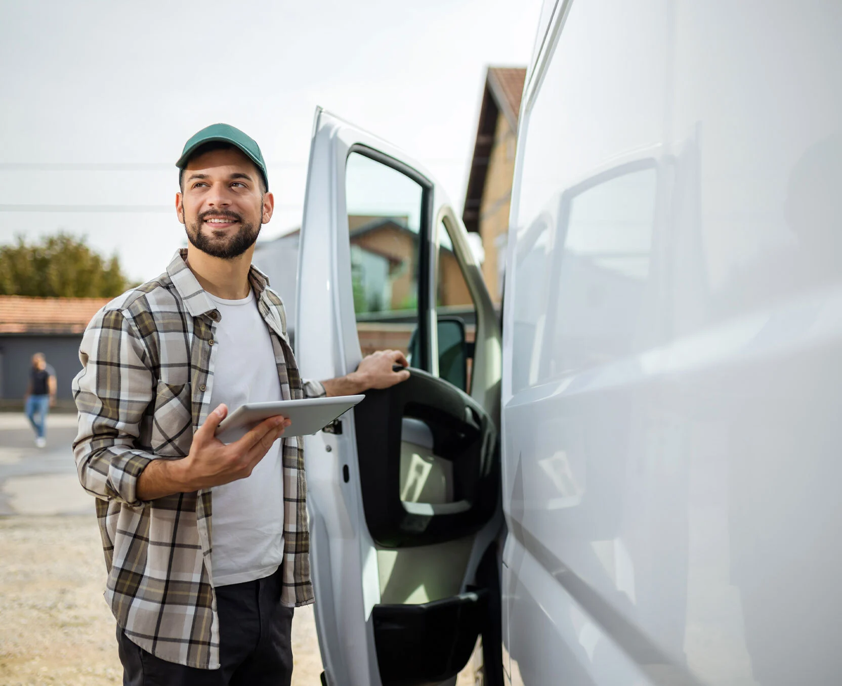 Kierowca dostawczy z tabletem wysiada z furgonetki.