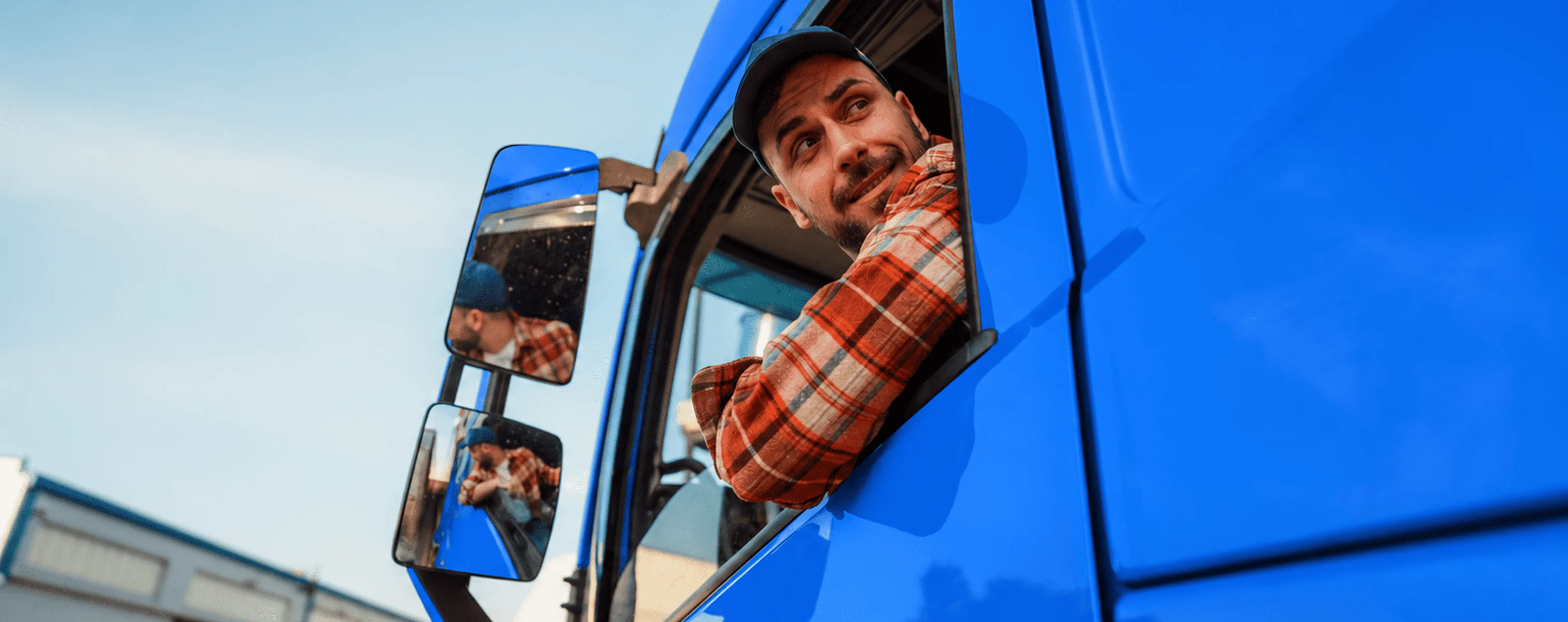 Mann lehnt sich aus dem Fenster eines blauen LKW