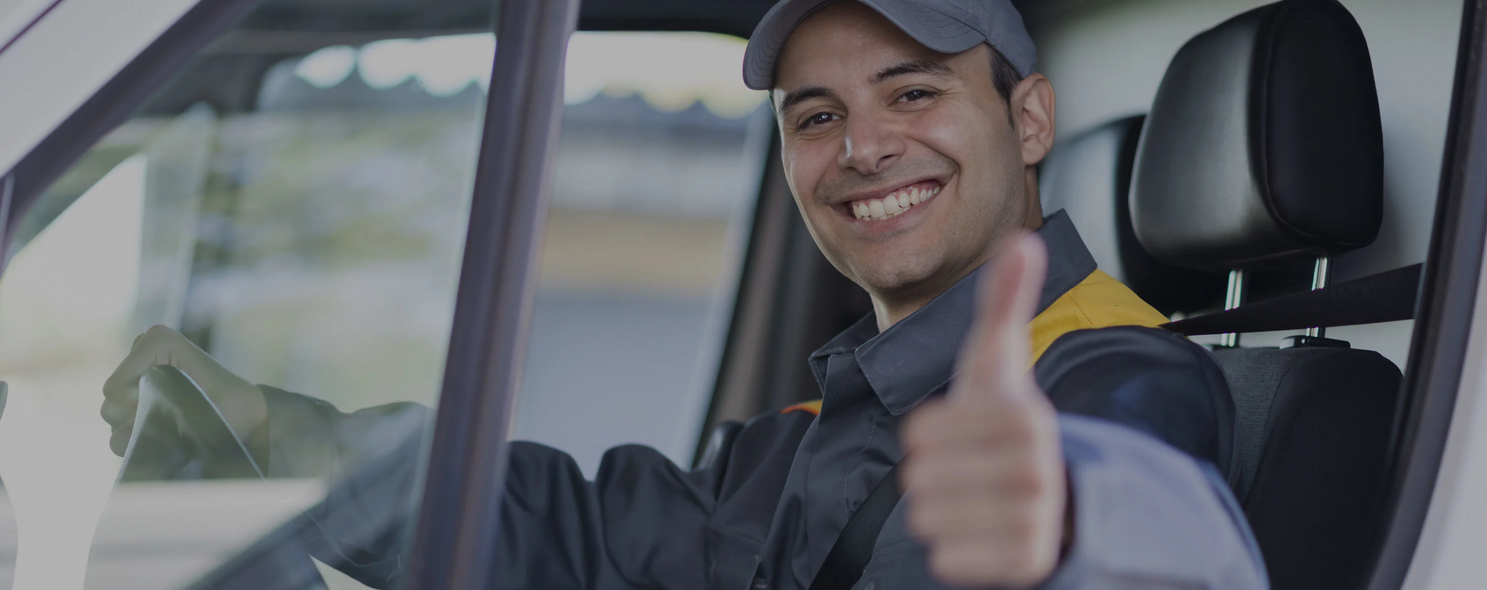 Een Belgische chauffeur in een voertuig steekt zijn duim omhoog.
