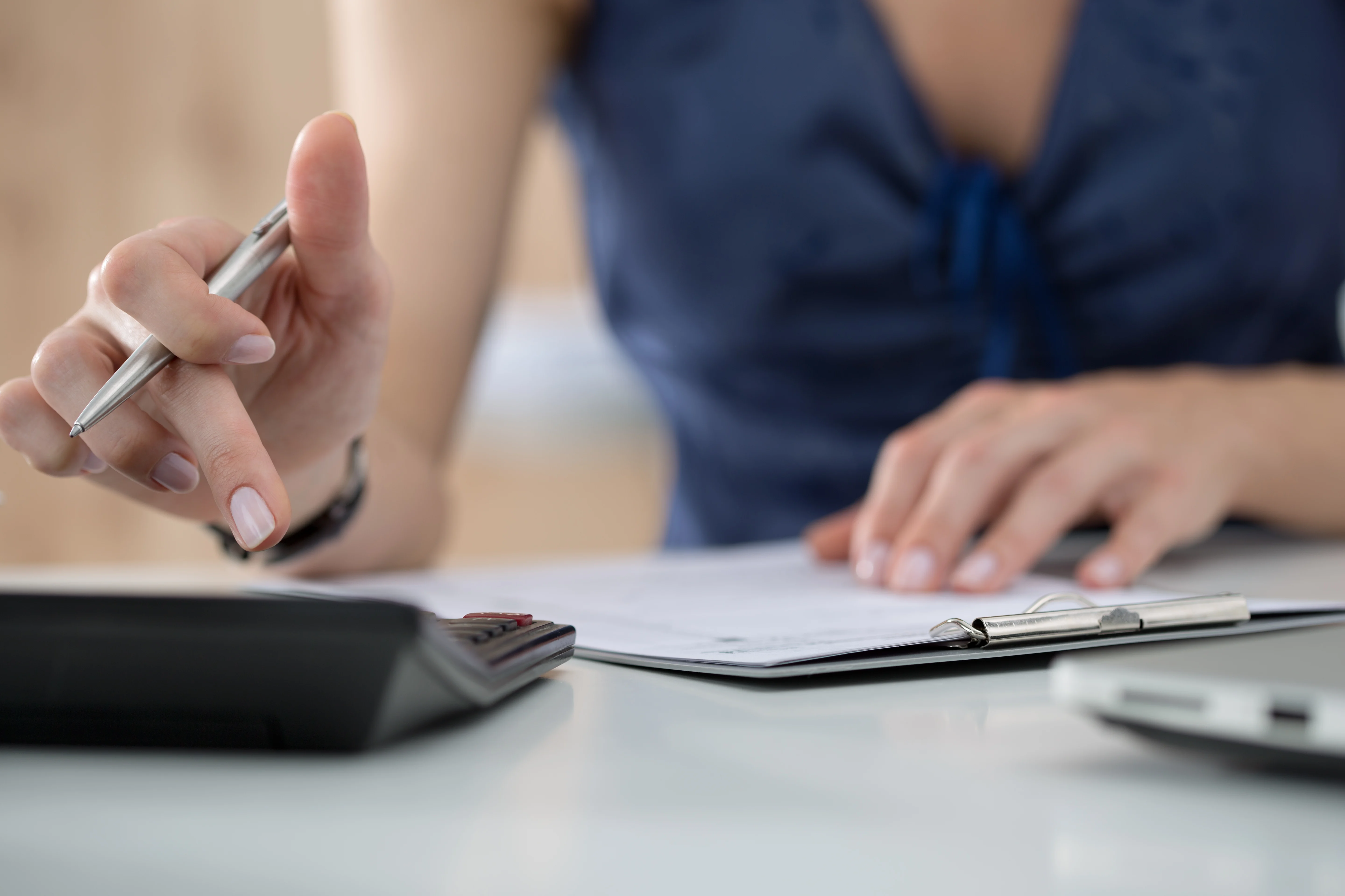 Gros plan sur la main d’une collaboratrice utilisant une calculatrice pour estimer l’ATN lié aux cartes carburant d’entreprise.