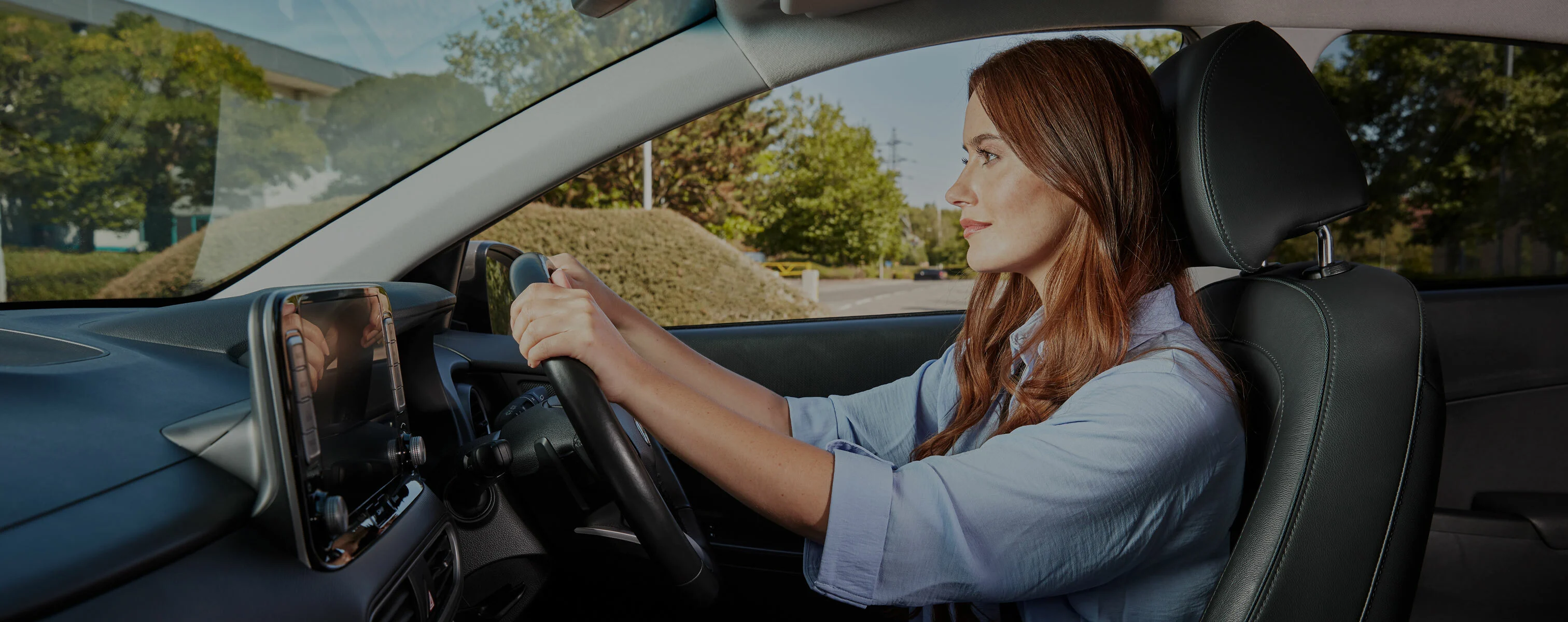 Vrouw zit achter het stuur van een auto en rijdt geconcentreerd.