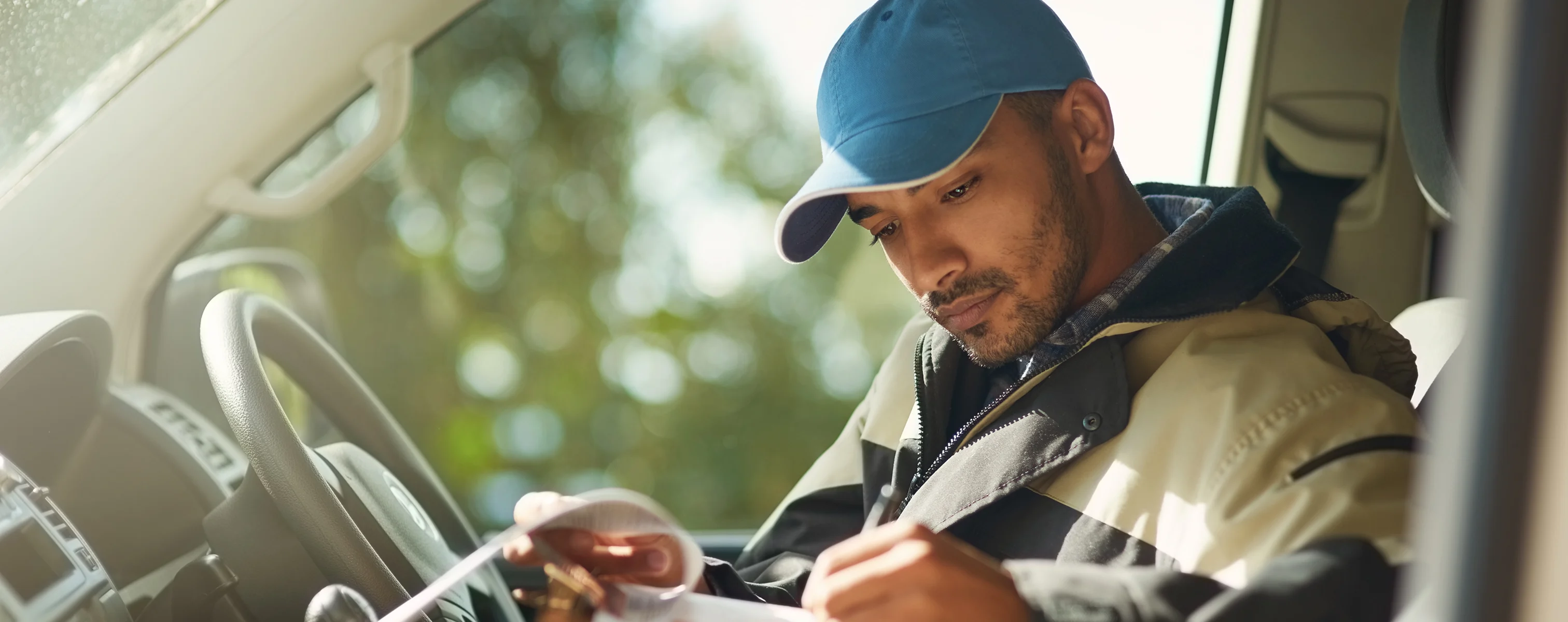 Lieferfahrer im Fahrzeug bestätigt Lieferung durch Unterschrift auf einem Paket