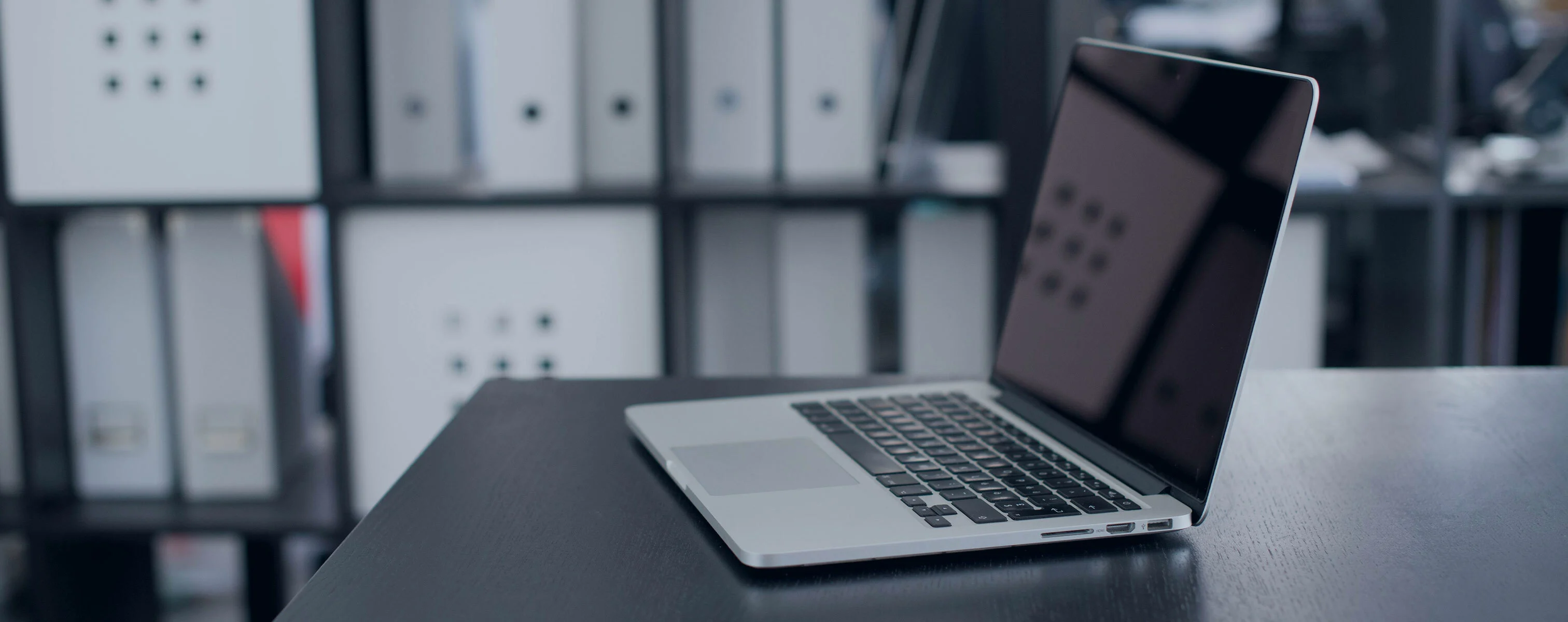 A laptop placed on a desk with shelves of folders in the background, showcasing a modern office environment.