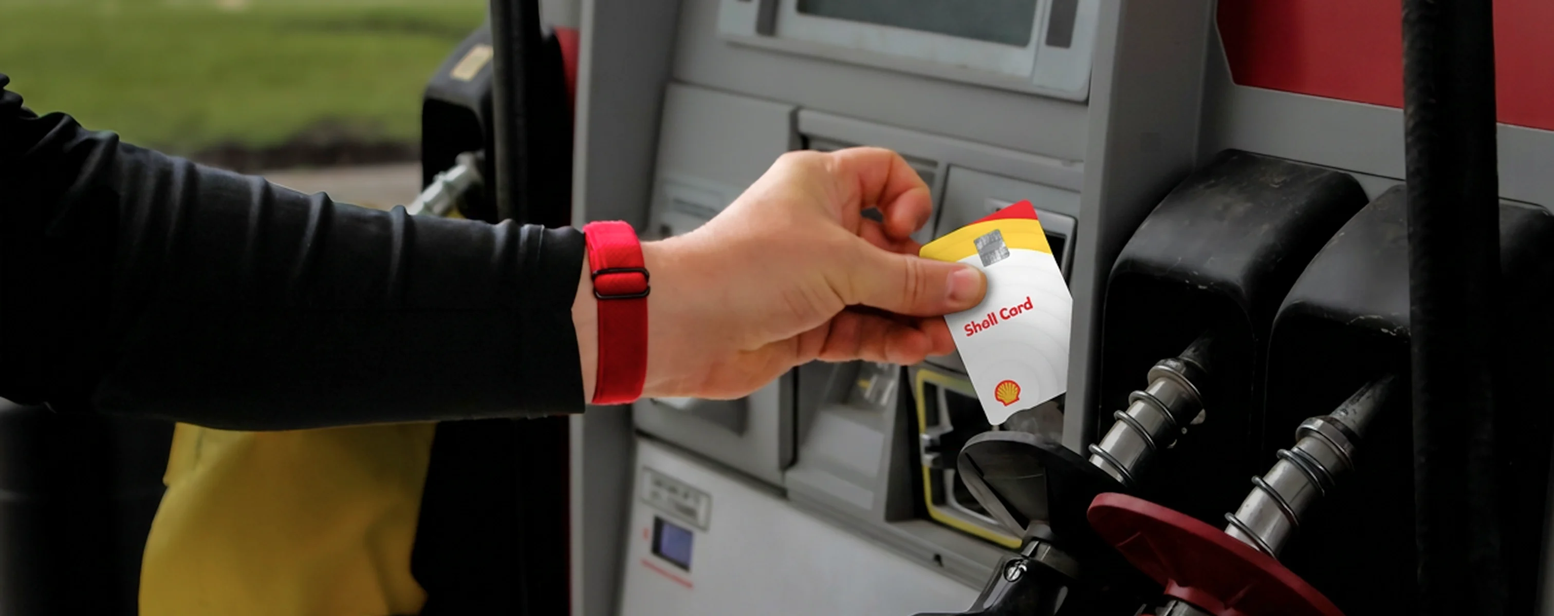 Zapfsäule an einer Tankstelle, Person hält eine Tankkarte an das Terminal neben der Zapfpistole zum bargeldlosen Bezahlen
