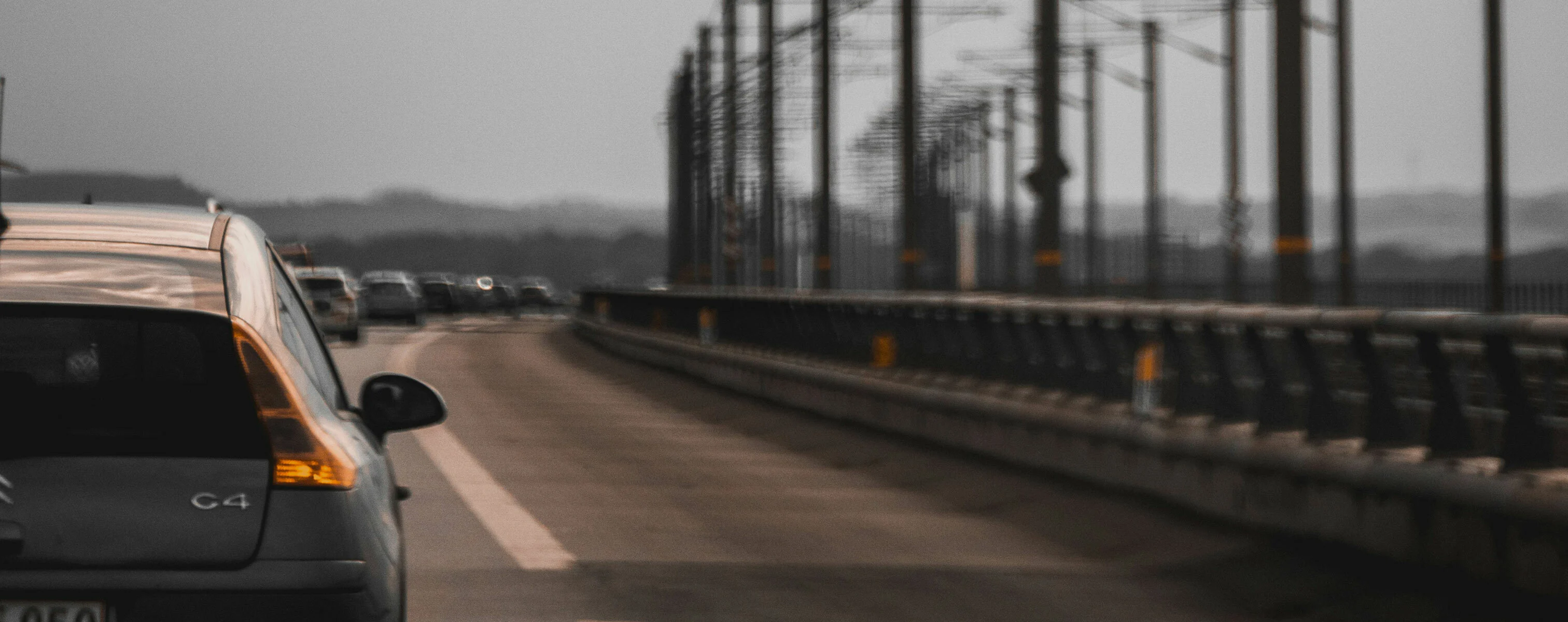 Auto fährt auf einer Brücke bei grauem Himmel.