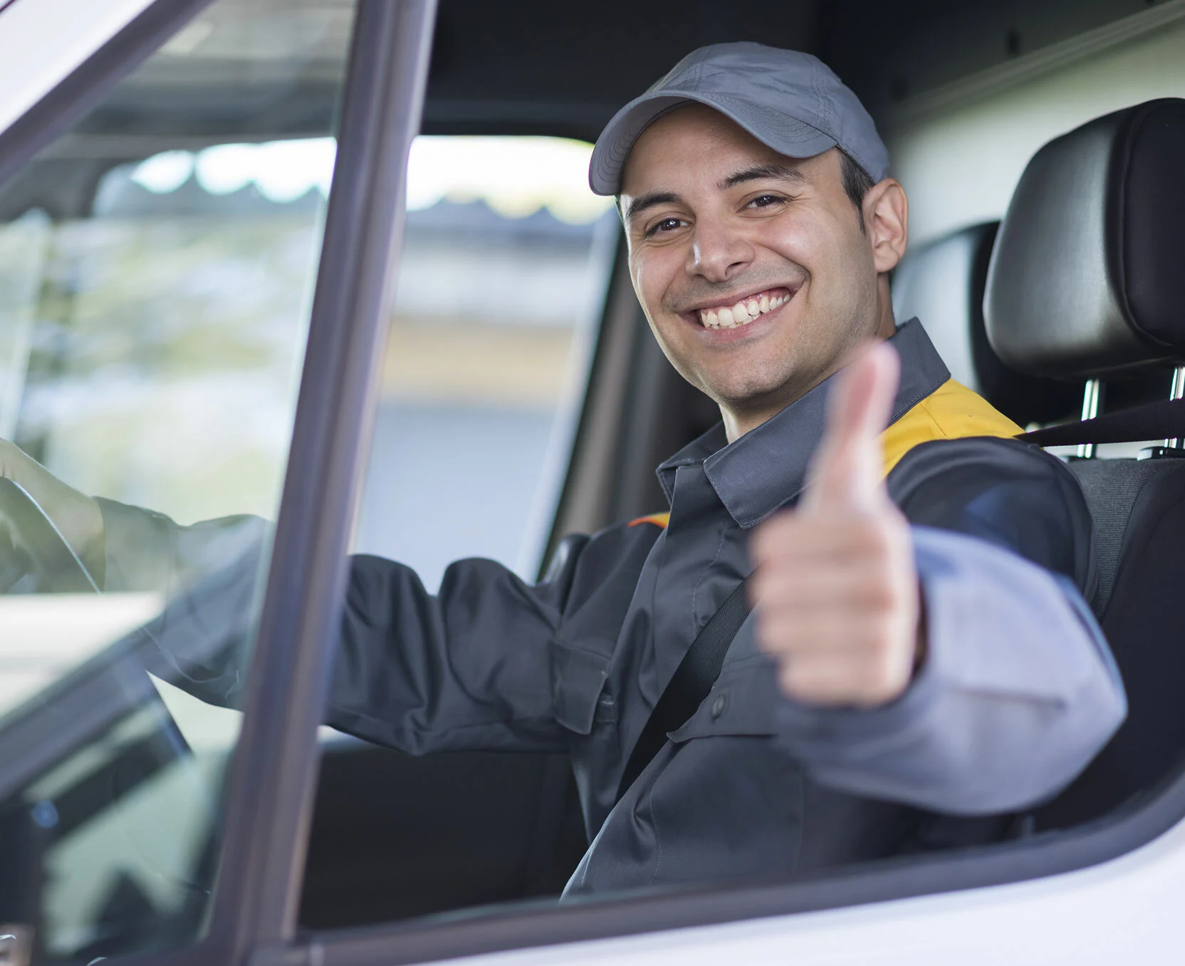 Uśmiechnięty kurier za kierownicą trzyma kciuki w górę