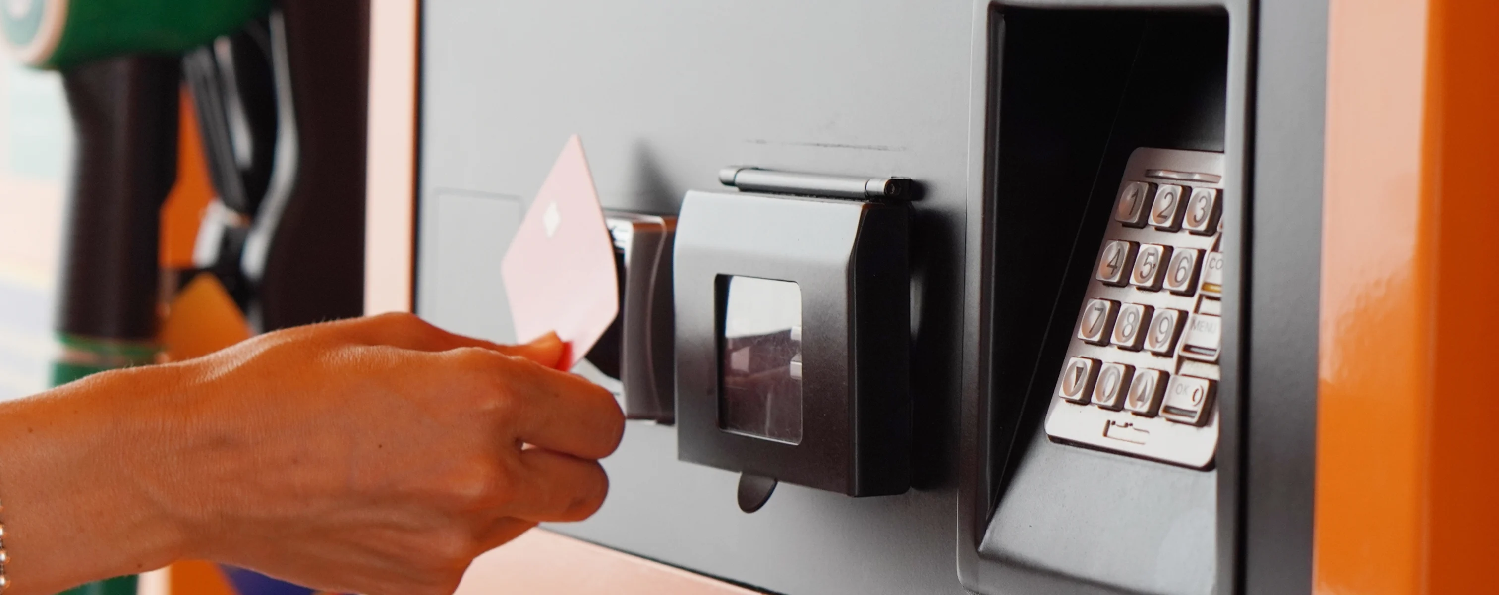 Person hält eine Tankkarte an ein Lesegerät an der Zapfsäule, daneben ist ein Tastenfeld zur PIN-Eingabe sichtbar