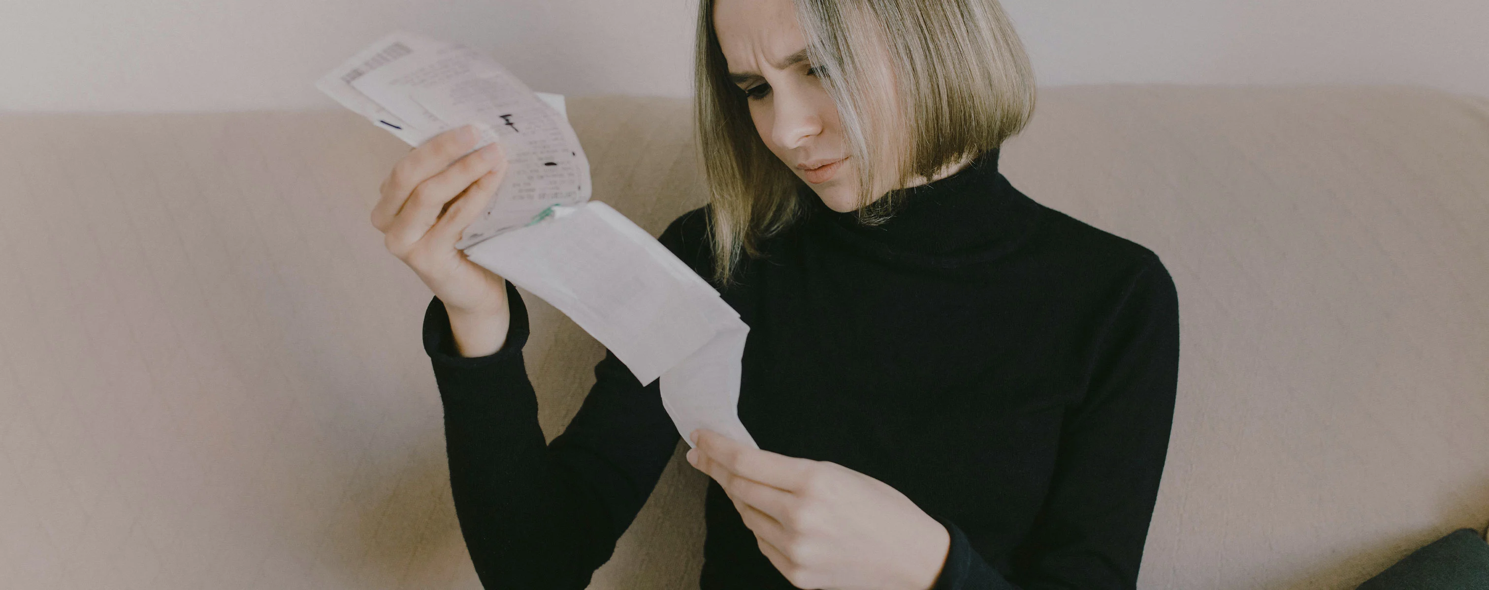 Een vrouw kijkt geconcentreerd naar bonnen die ze in haar handen houdt.