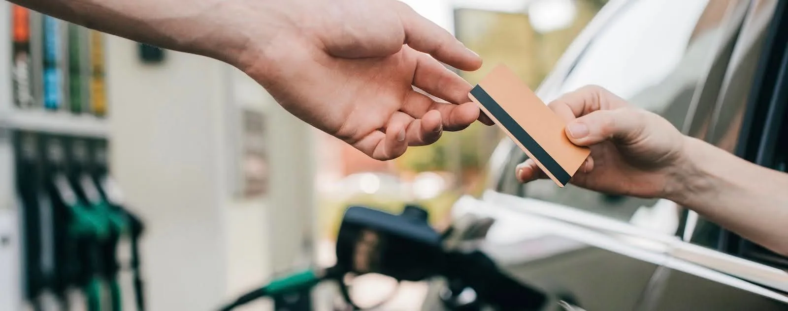 Un conducteur tend sa carte carburant pour payer son ravitaillement à une station-service.