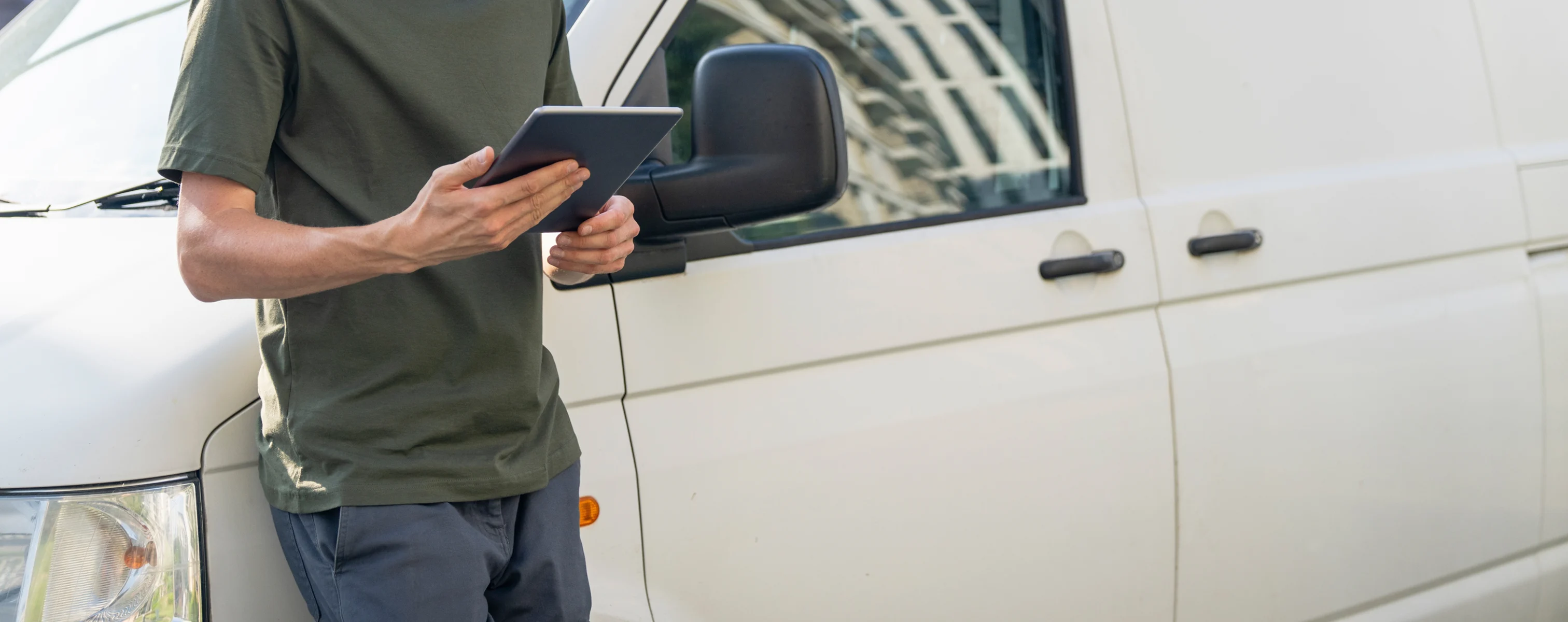 Mann mit Tablet vor Lieferfahrzeug bei der Organisation von Transportaufträgen