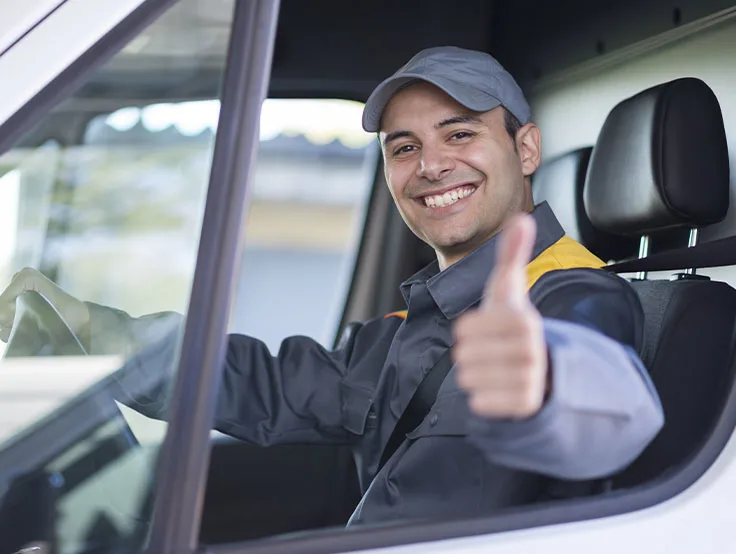 Un conducteur souriant dans un véhicule de société lève le pouce.