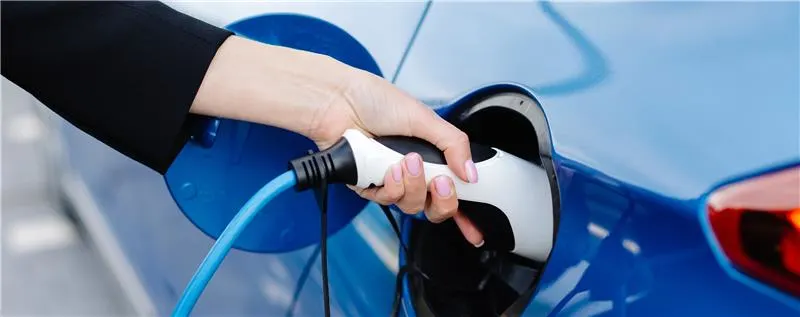 Elektroauto wird an einer Ladestation aufgeladen – Nahaufnahme des Ladevorgangs mit eingestecktem Ladekabel an einem blauen Fahrzeug.