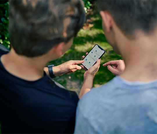 Two people using the Yalp+ app to find an interactive playset near them.