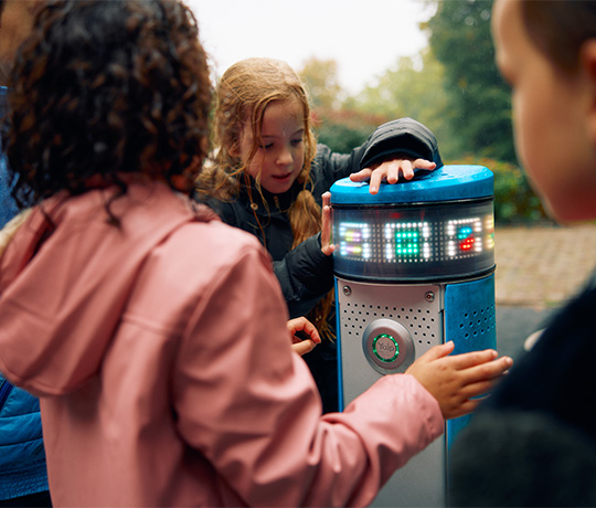 Children choosing a game to play on the Lappset Memo Interactive play pillars