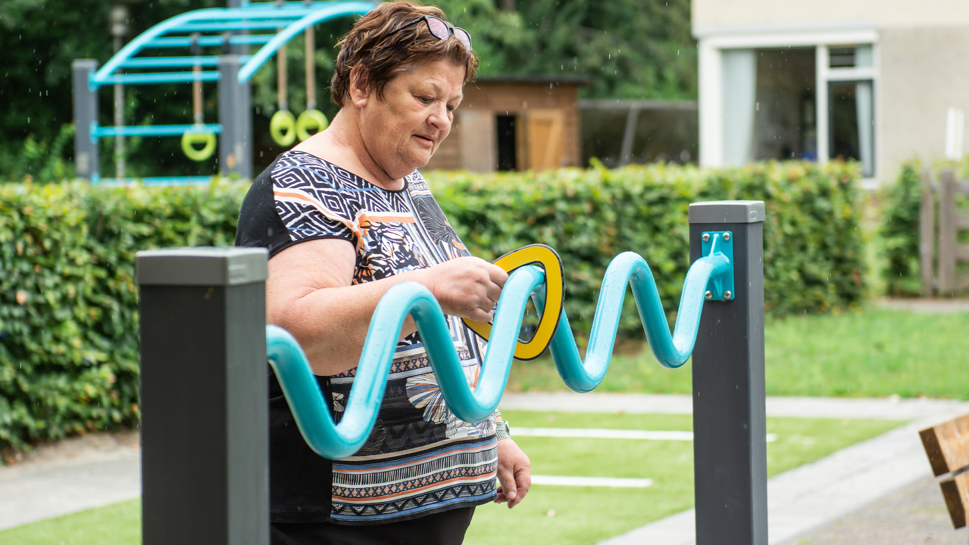 Senior woman using outdoor exercise equipment at Norschoten Care Organization's Generation Garden.