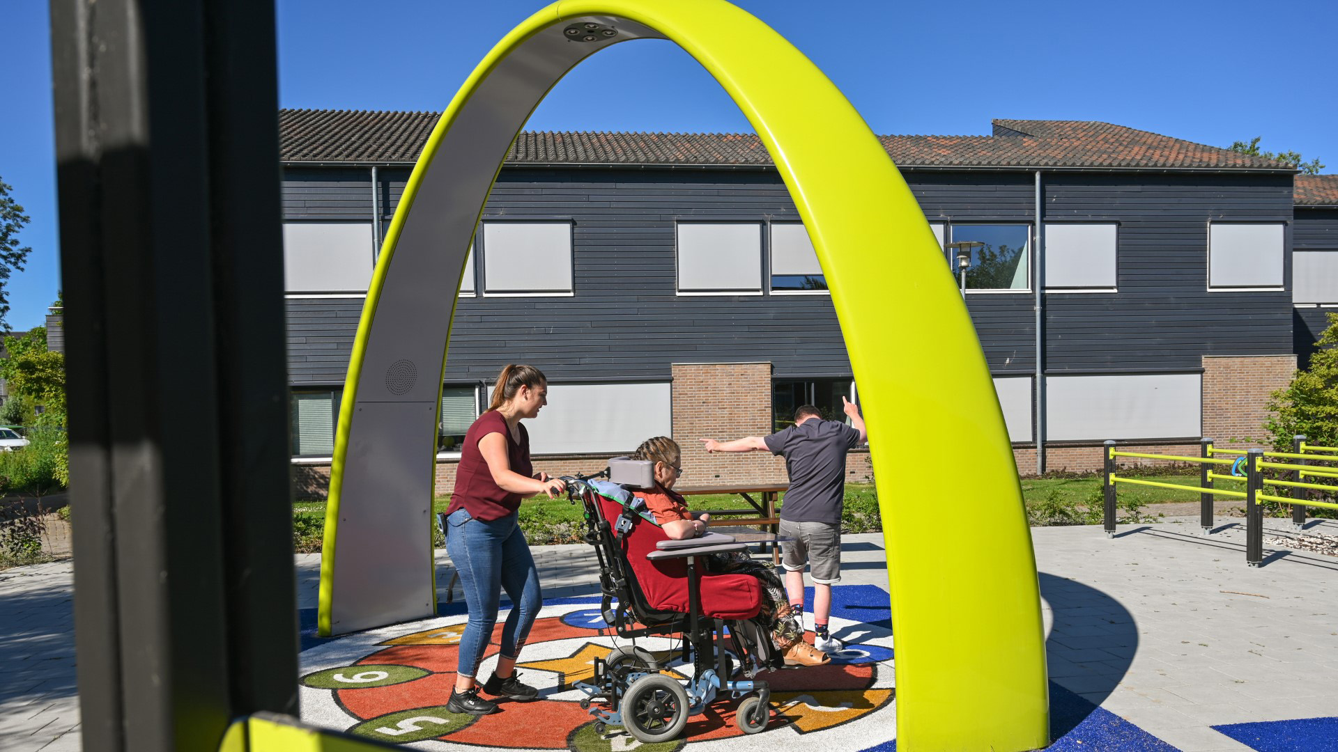 Residents and caregiver from Ipse de Bruggen playing together under the Lappset Sona Interactive dance and play arch
