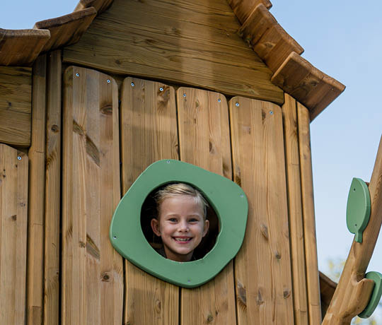Flicka tittar ut genom ett fönster på en Flora lekprodukt