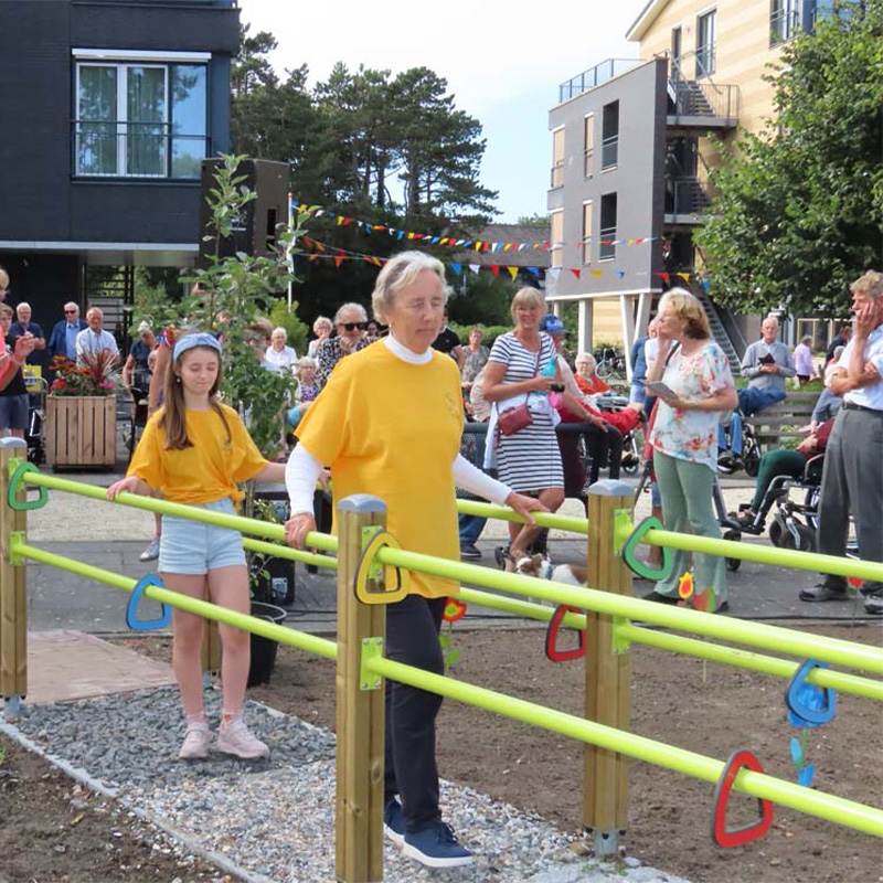 Seniors and children are participating in an outdoor activity at the Exercise Garden in Terschelling