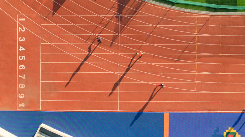 Une piste d’athlétisme est visible avec deux personnes en train de courir.