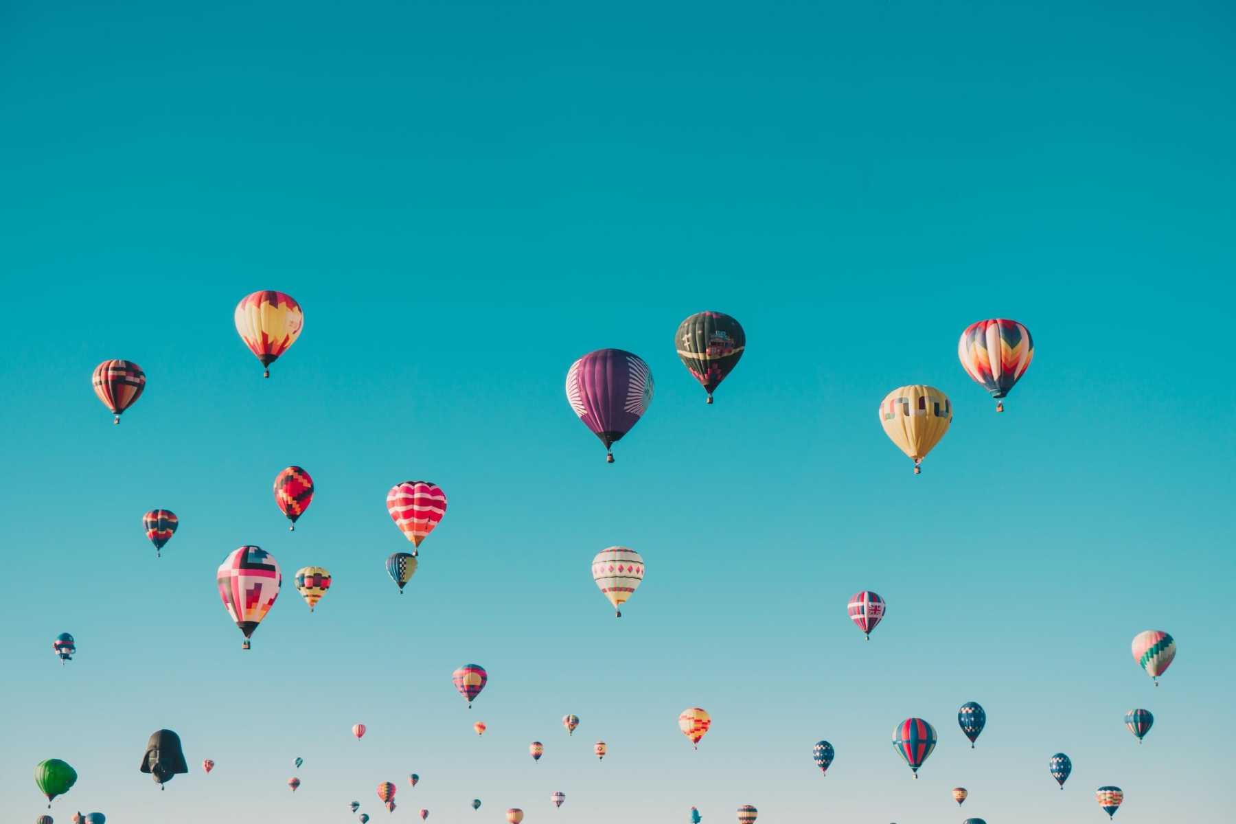 Dozens of hot air balloons against a blue sky