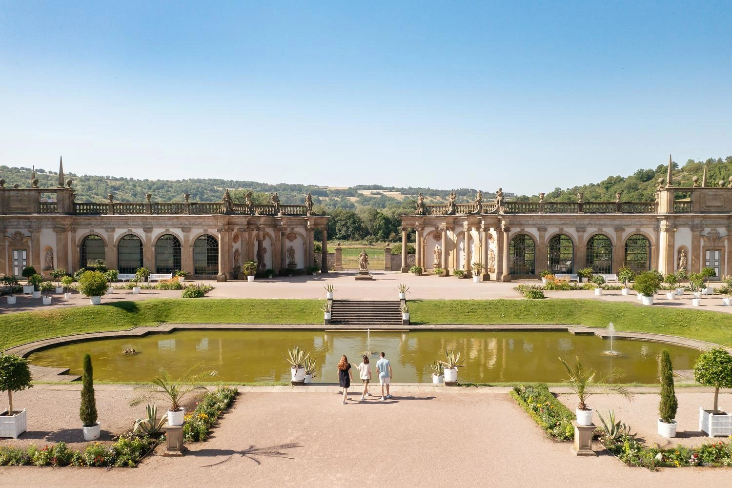 Weitläufige Gartenanlage eines Schlosses mit einem Teich in der Mitte