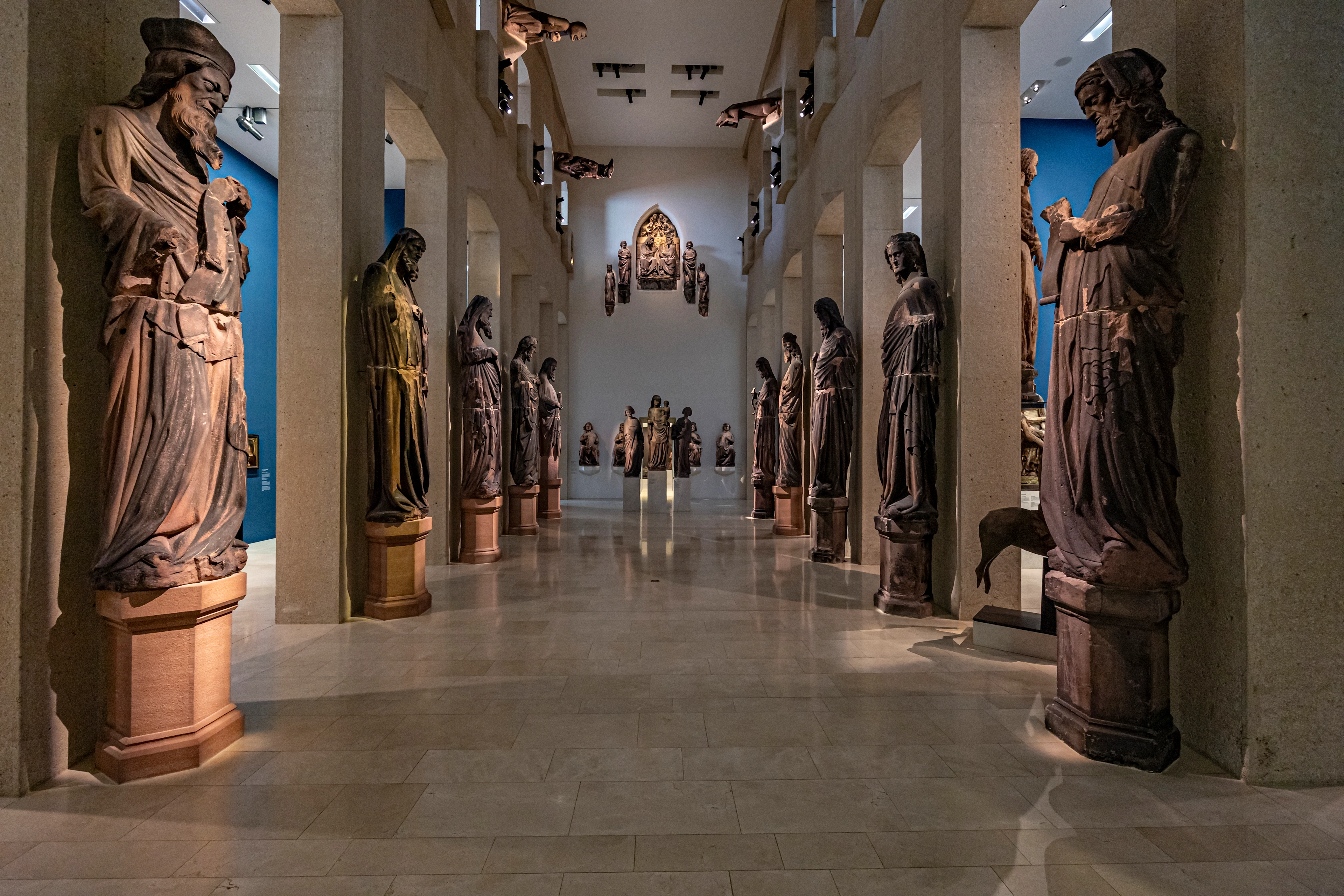 nnenansicht der Skulpturenhalle im Augustinermuseum Freiburg mit historischen Steinfiguren in einer modernen, hohen Galerie.