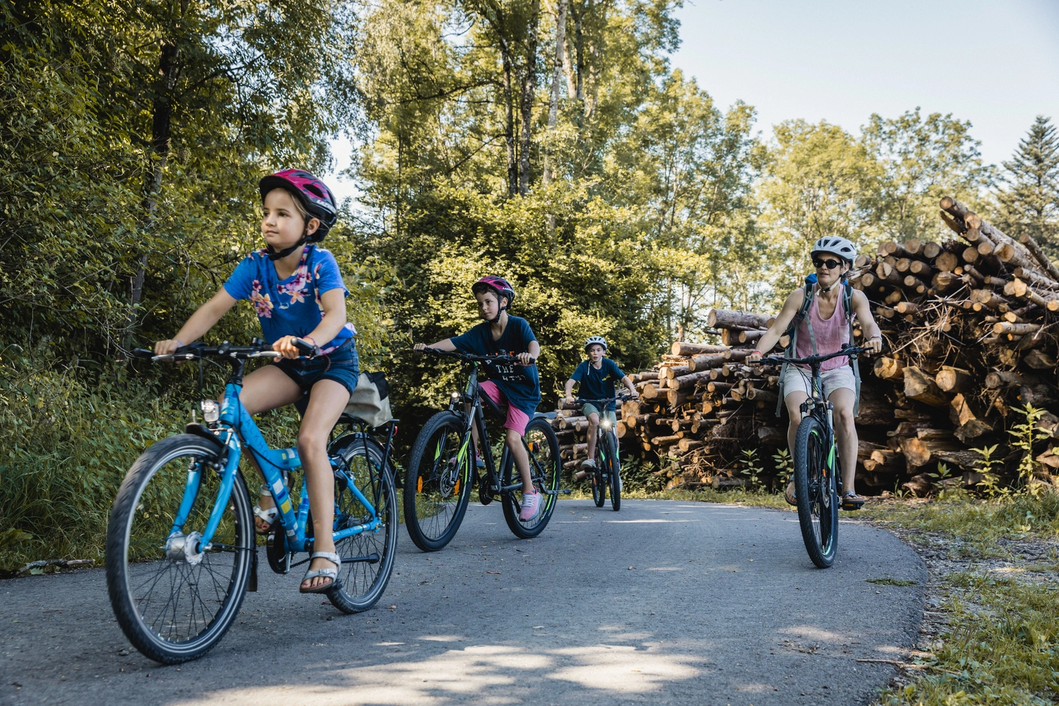 Eine Familie fährt mit ihren Fahrrädern auf einem Waldweg.