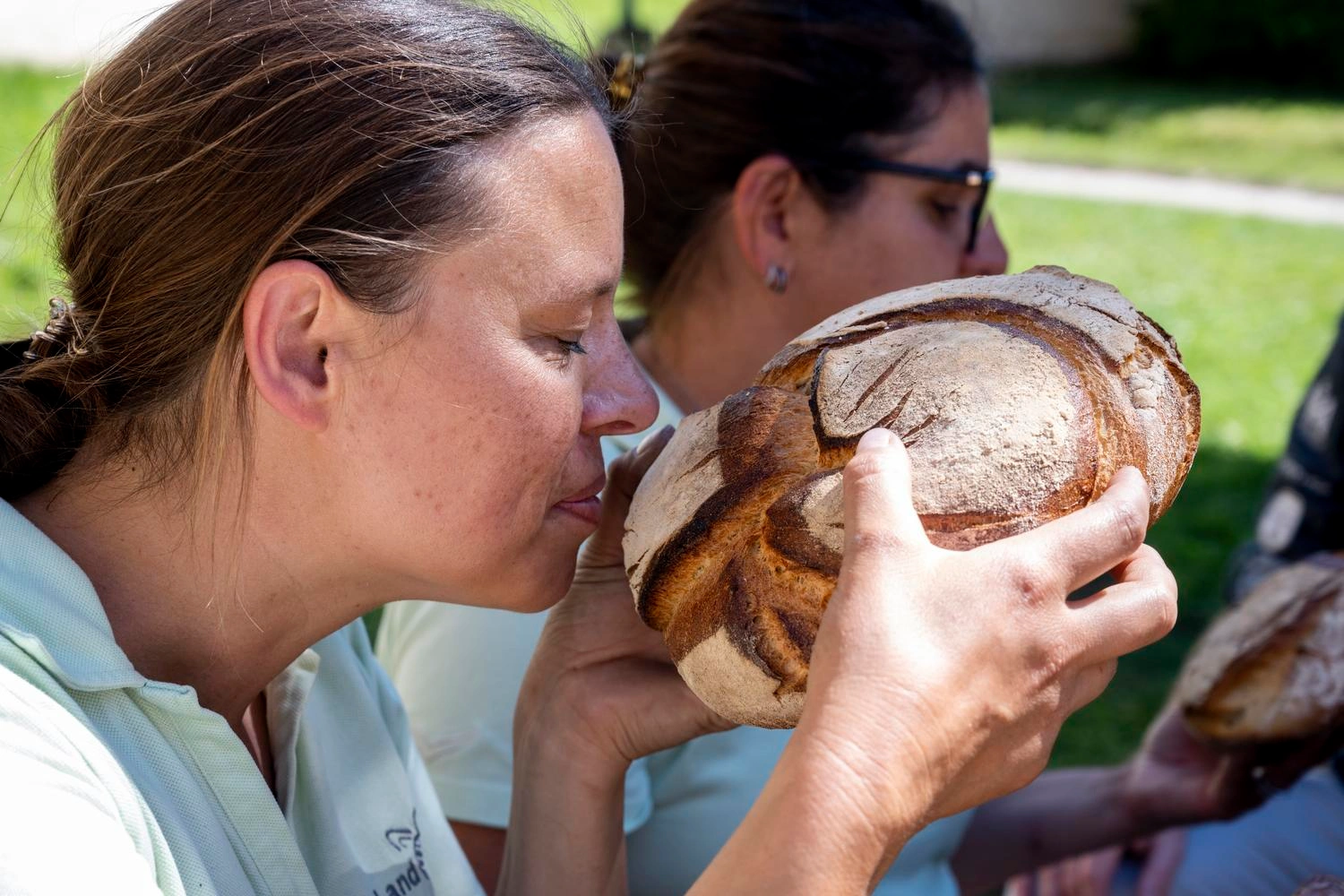 Eine Frau riecht an einem frischen Laib Brot.