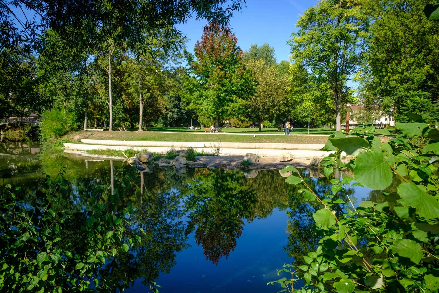 View of a newly created waterfront promenade with lush greenery and neighbouring parkland.