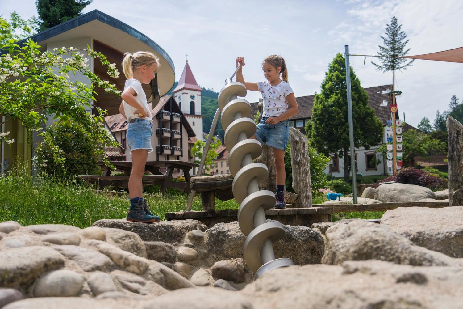 Zwei Mädchen spielen an einem Wasserspiel auf einem Spielplatz