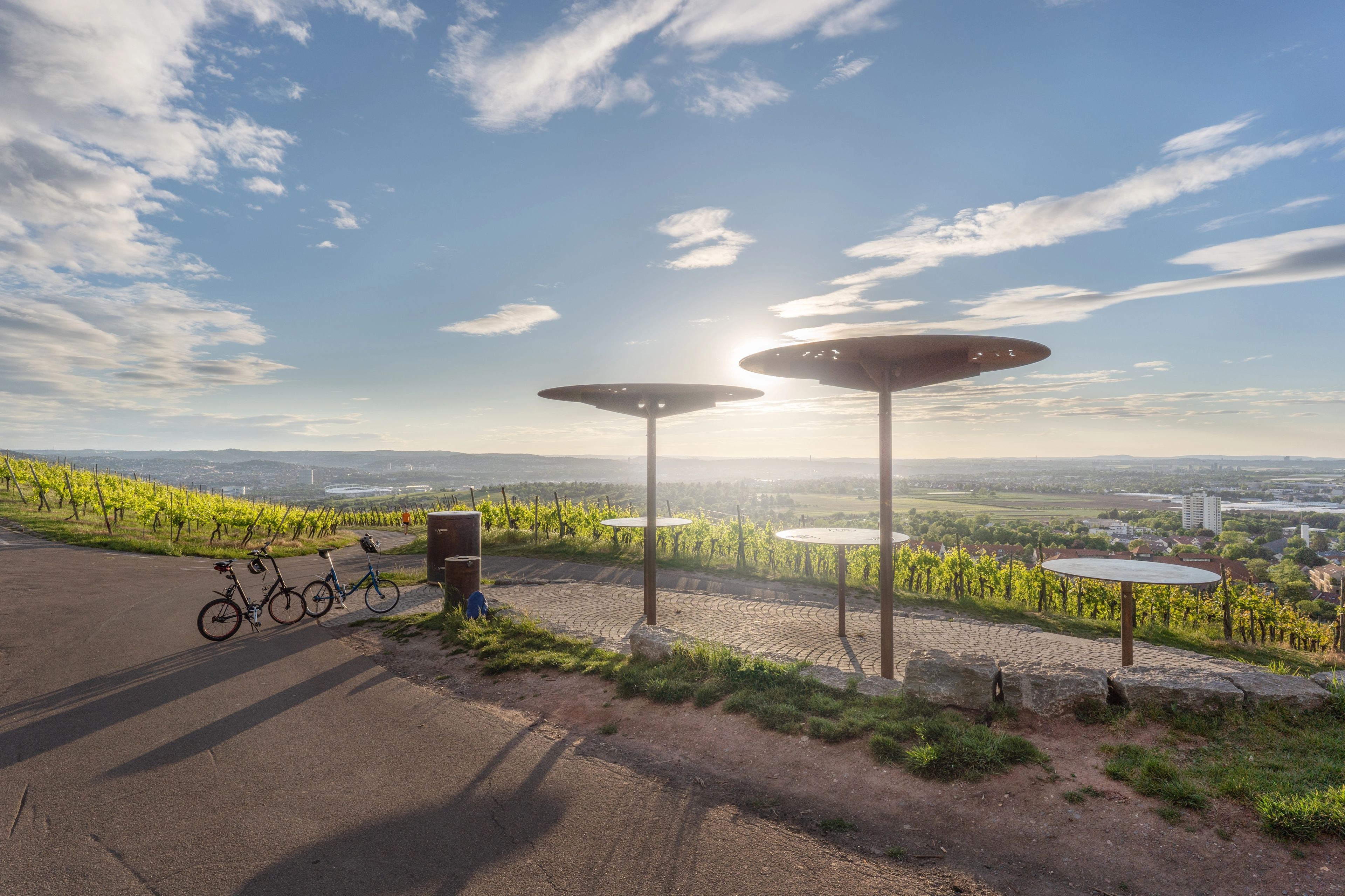 Aussichtspunkt im Weinberg bei Fellbach im Remstal mit Sitzscheiben, abgestellten Fahrrädern und weitem Blick über die Stadt und Landschaft, als Motiv für Rad‑ und Weintourismus.