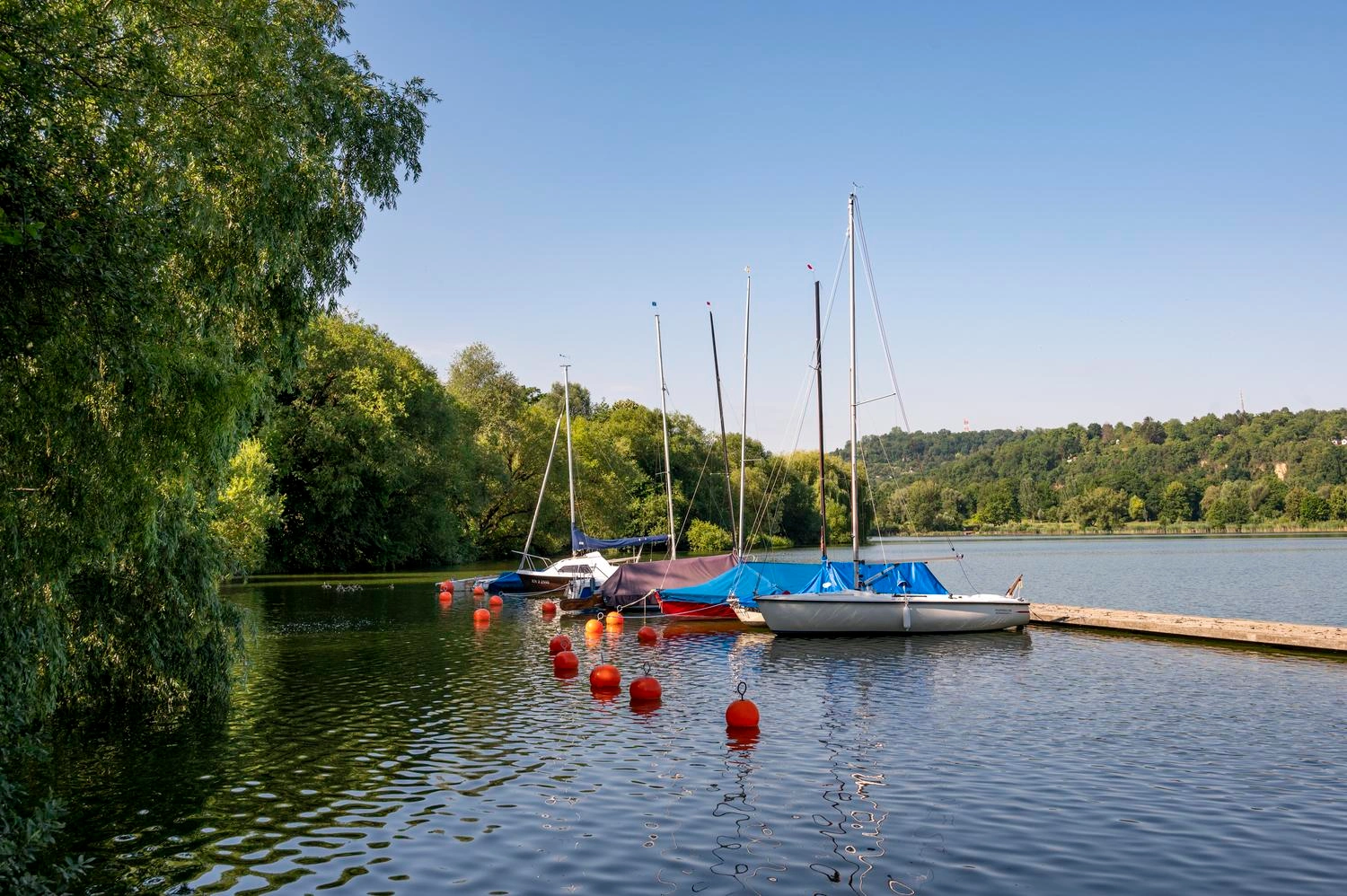 Several sailing boats moor at a jetty in the middle of a lake