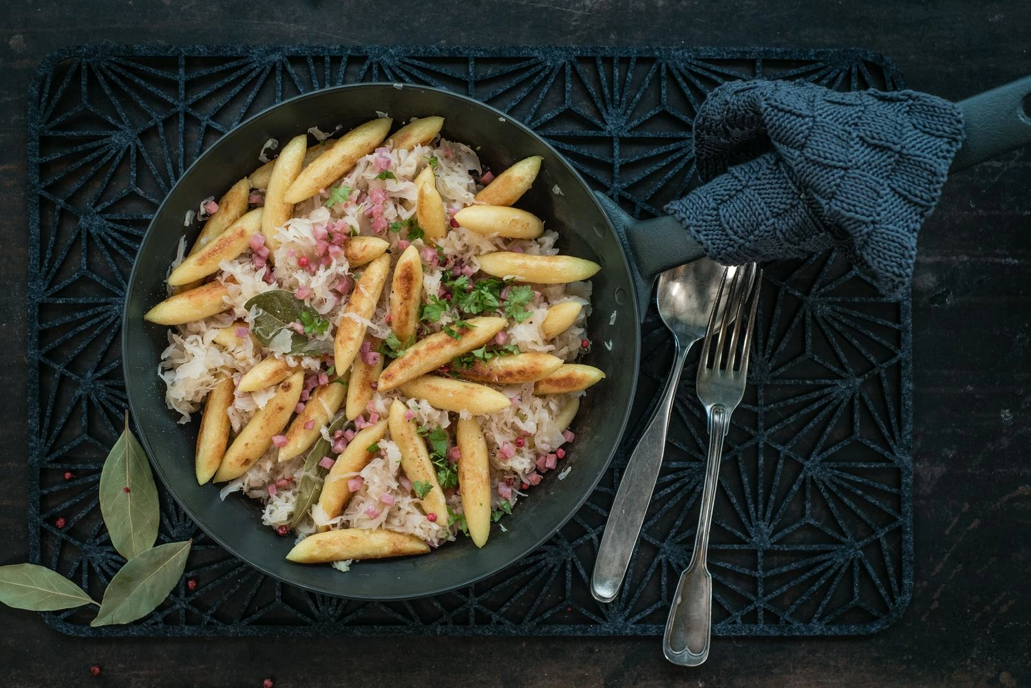 Top view of a plate of KRautschupfnudeln on a dark table with dark crockery.