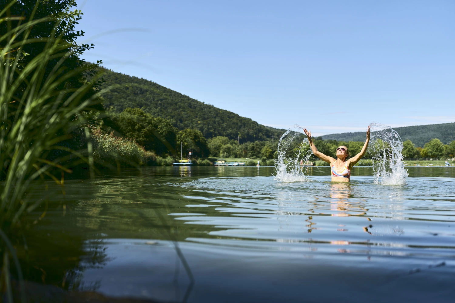 Person beim Baden in einem Natursee im Taubertal bei Freudenberg an einem sonnigen Sommertag.