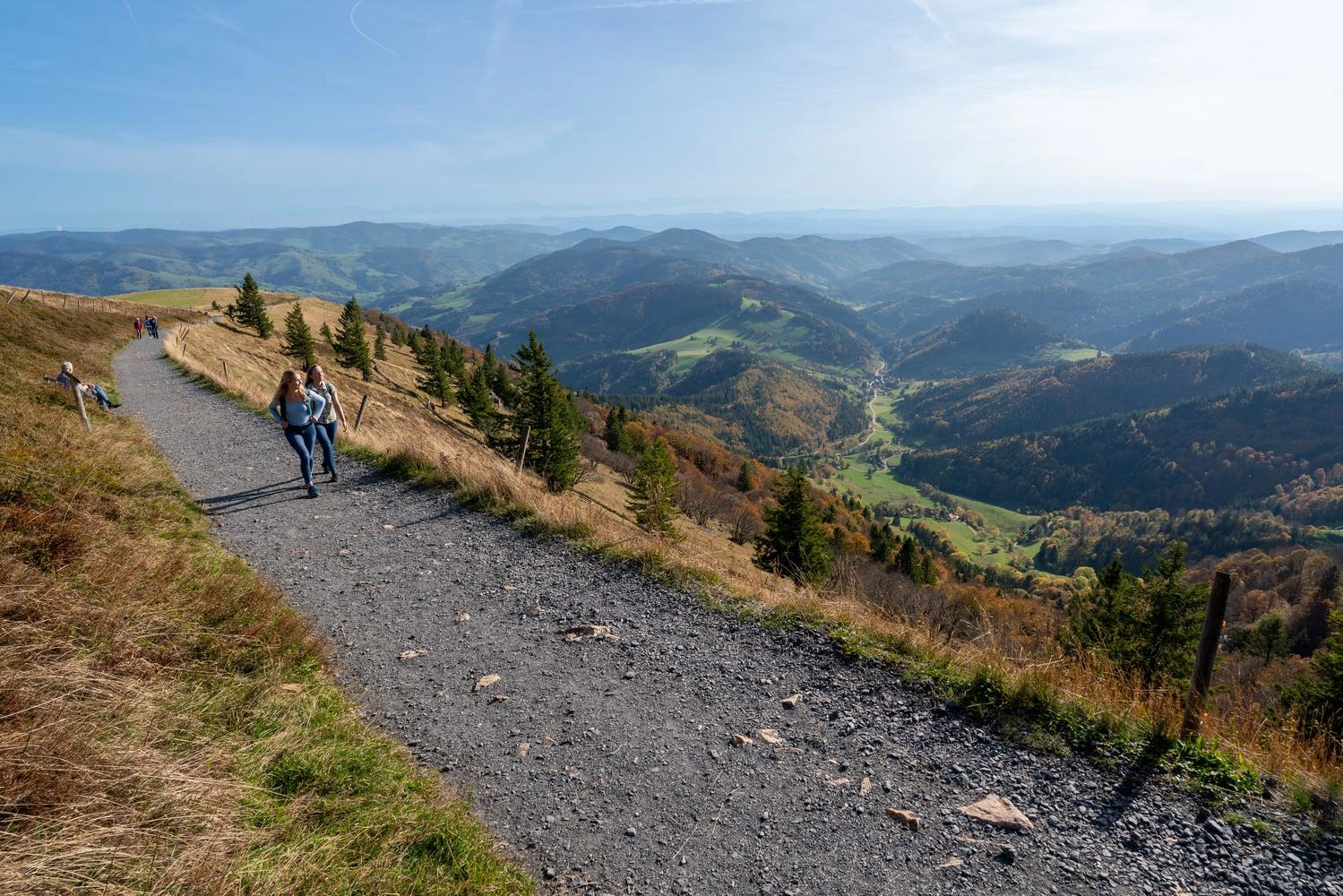  Two people on a hiking trail with a fantastic panorama to the left.