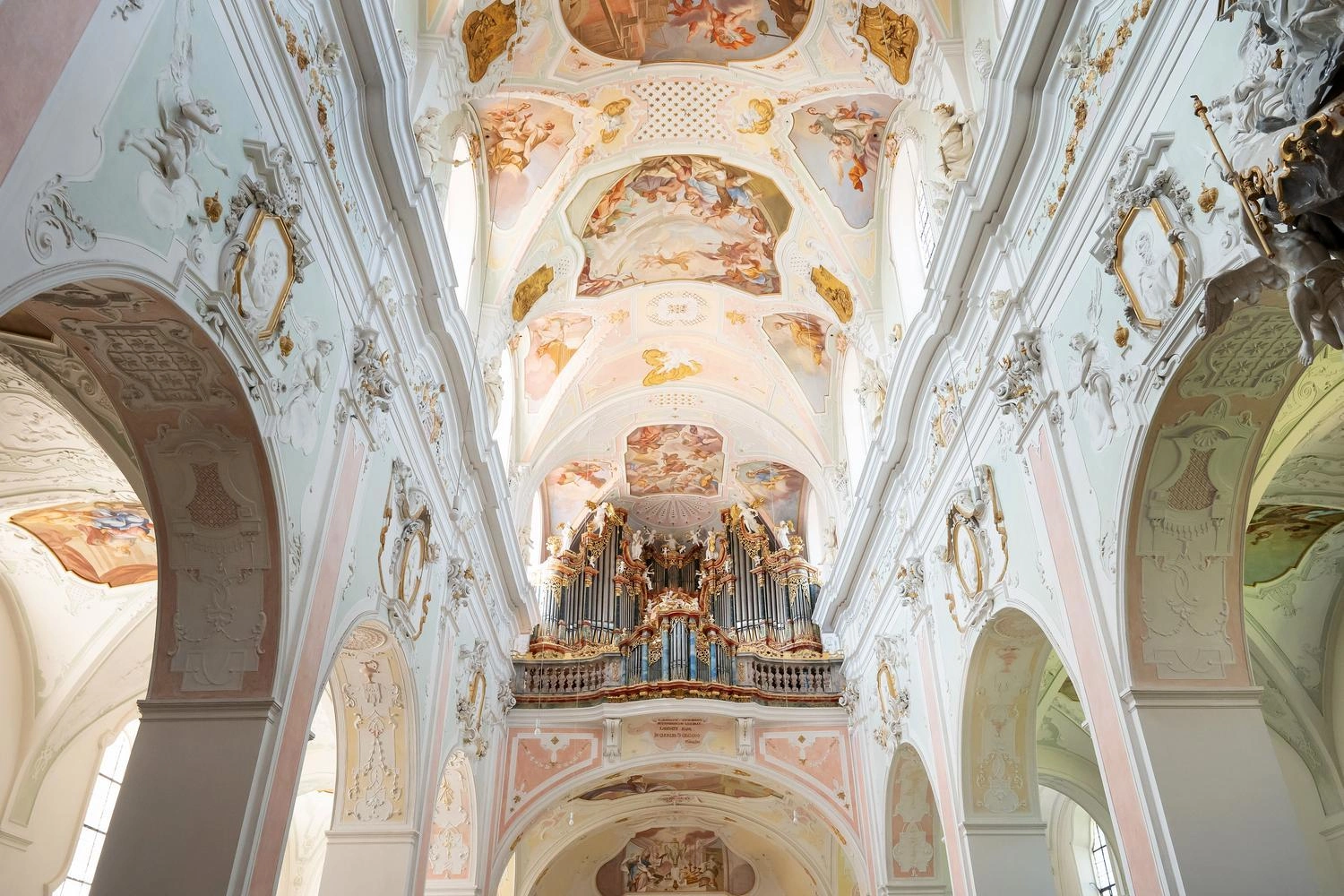 Prächtiges Kircheninnere mit barocken Deckenfresken und einer reich verzierten Orgel am Ende des Hauptschiffs.