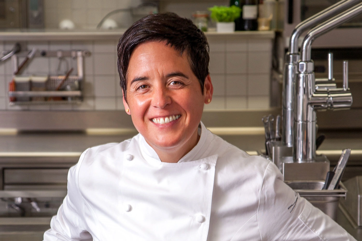 A portrait of a female chef in a kitchen.