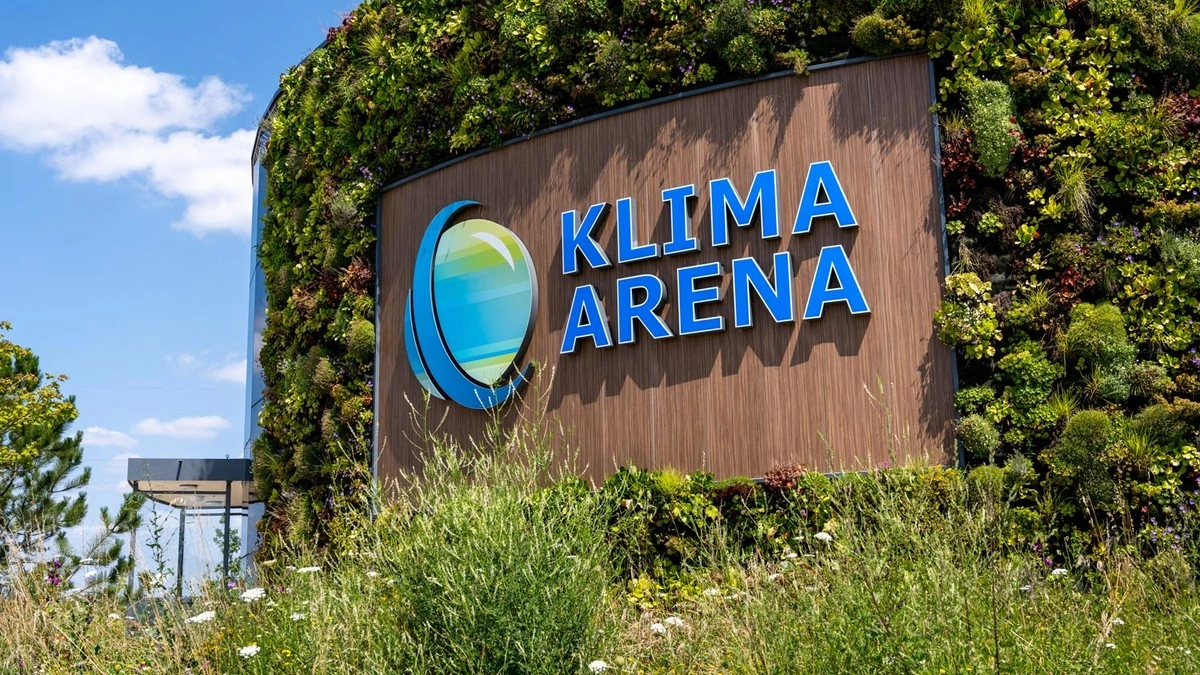 A sign with the inscription ‘Klima Arena’ on an overgrown façade.