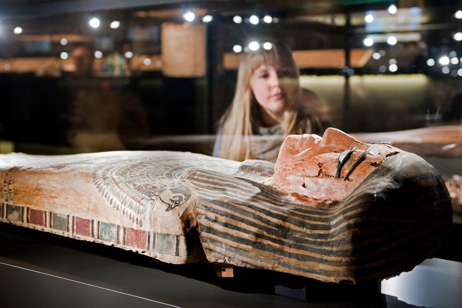 Eine Frau schaut sich ein Originalexponat aus dem alten Ägypten in einem Museum an. 
