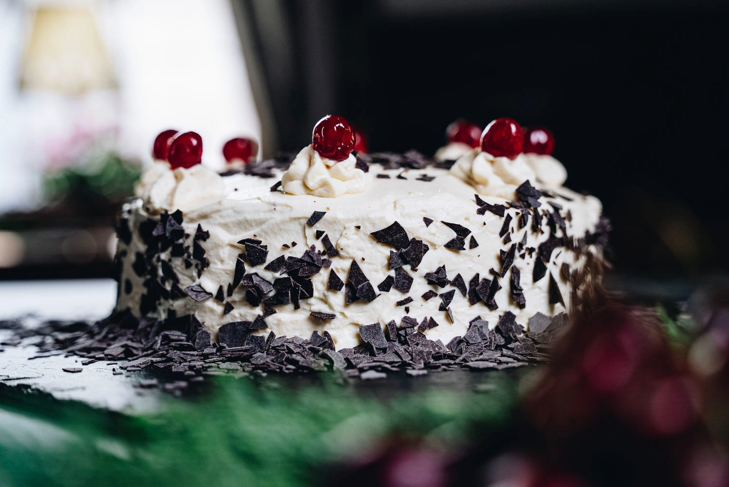 Schwarzwälder Kirschtorte mit Sahne, Kirschen und dunklen Schokoladenraspeln auf einer Platte – klassische deutsche Spezialität in eleganter Präsentation.
