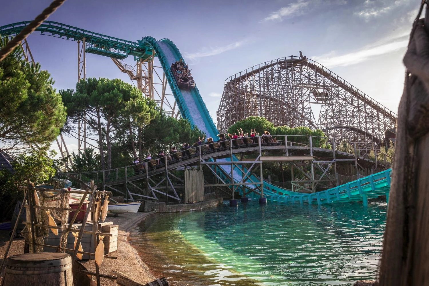 Wasserachterbahn mit Boot auf steiler Abfahrt im Europa-Park, umgeben von Wasser, Bäumen und einer Holzachterbahn im Hintergrund.