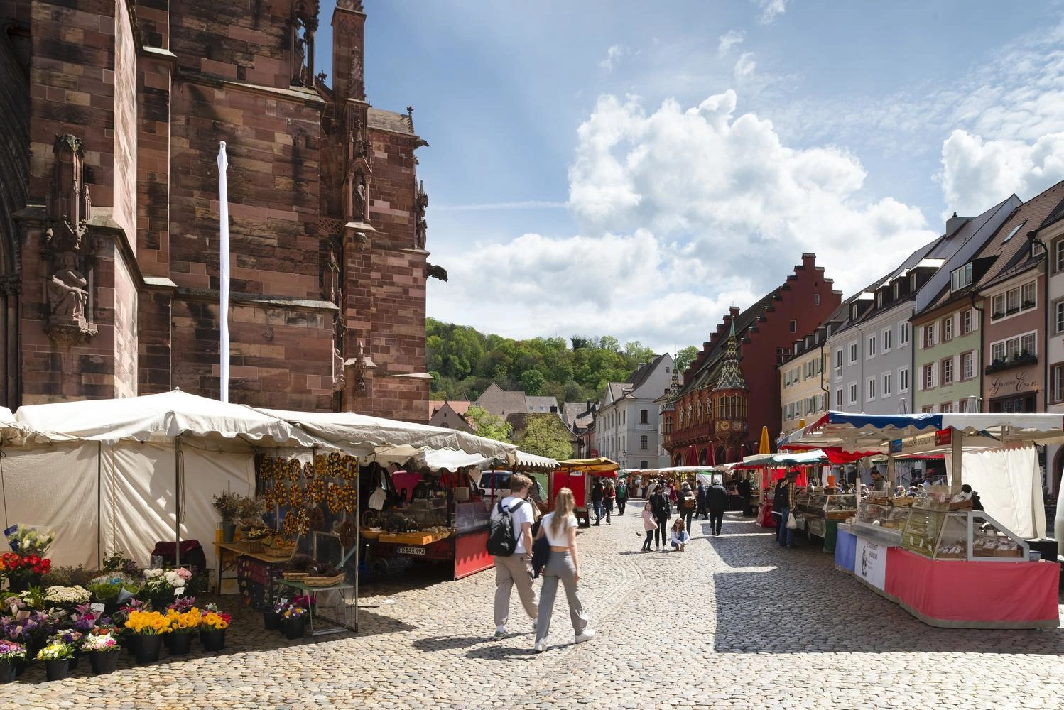 People stroll through the market on Münsterplatz past the stalls.