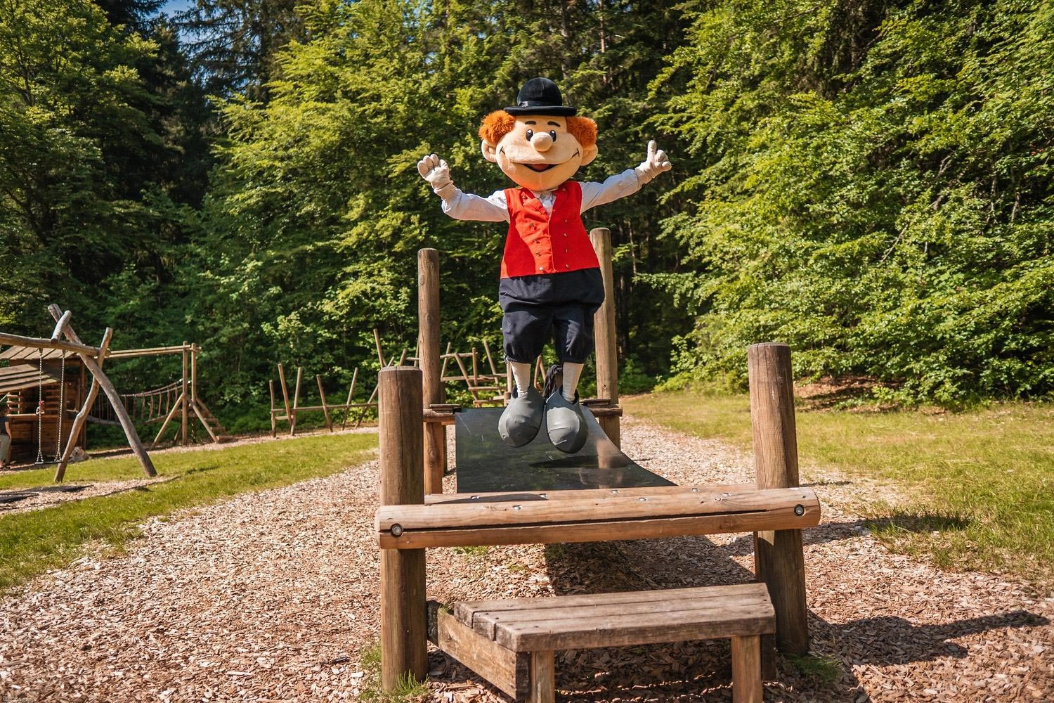 Ein Maskottchen springt auf einer Brücke auf einem Spielplatz auf und ab.