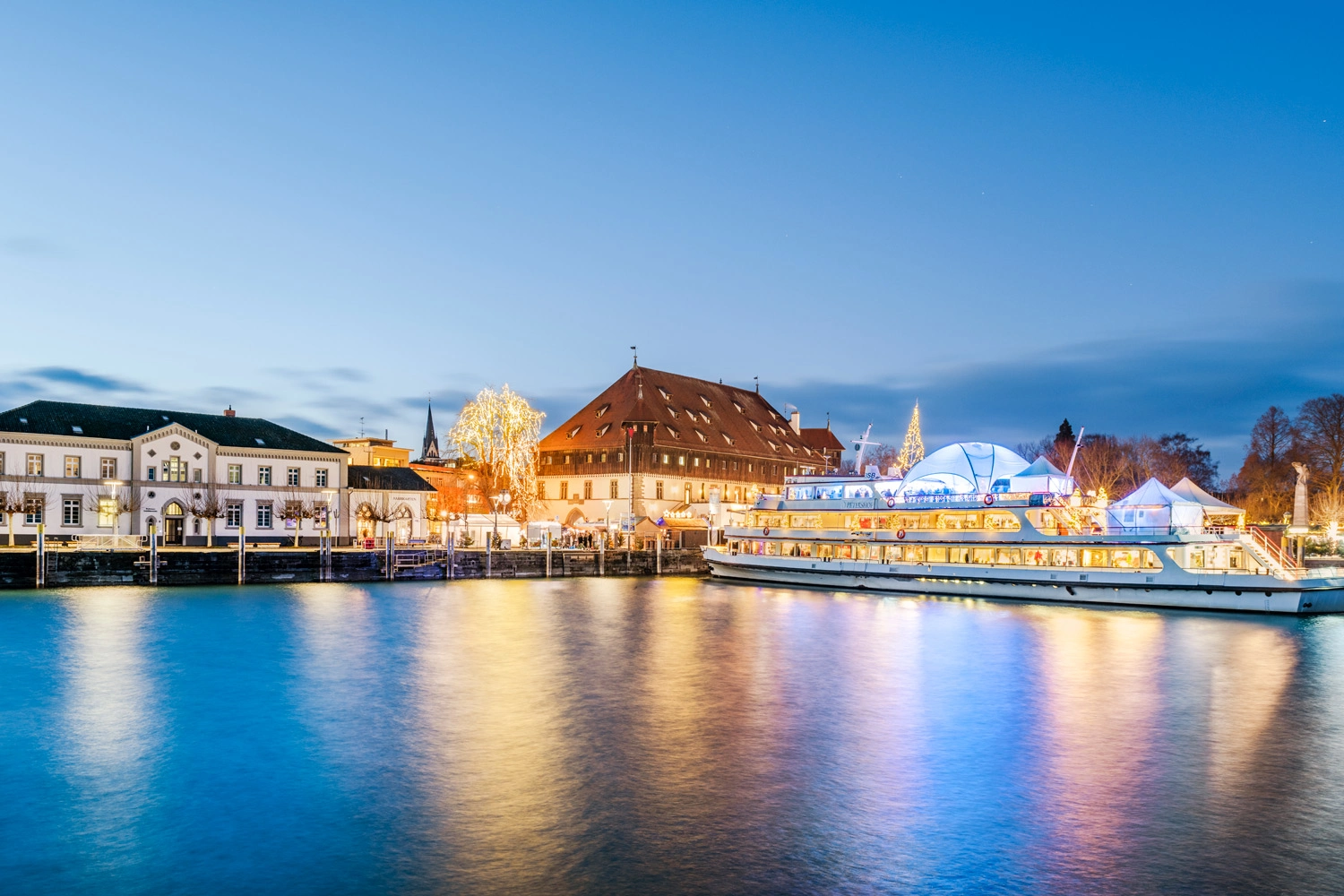 Blick auf einen weihnachtlichen Hafen mit einem beleuchteten Schiff